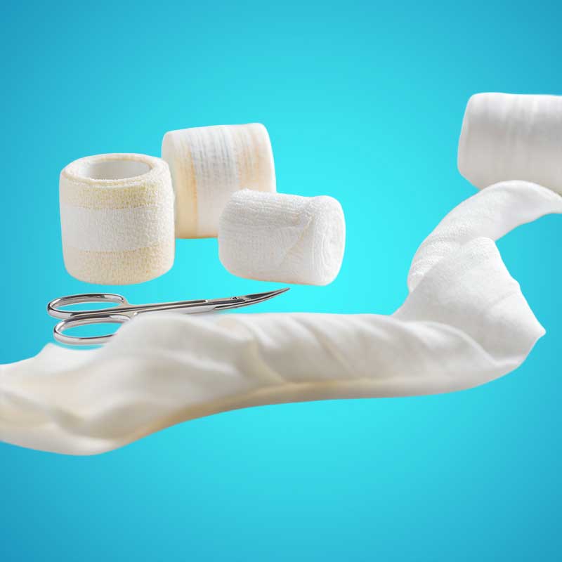 Specialty Needs Supplies: Medical gauze rolls, a pair of surgical scissors, and a length of unrolled bandage are arranged on a blue background.
